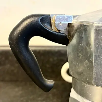 A close up of the moka pots black handle