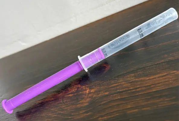 A close up of the syringe from a calpol bottle with the inner cylinder pulled all the way out