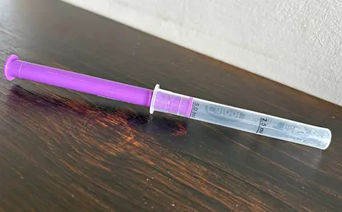 A close up of the syringe from a calpol bottle with the inner cylinder pulled all the way out