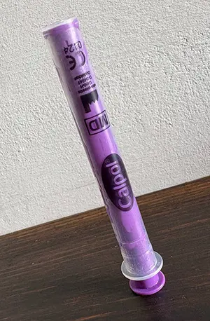 A calpol syringe balanced upright on its side