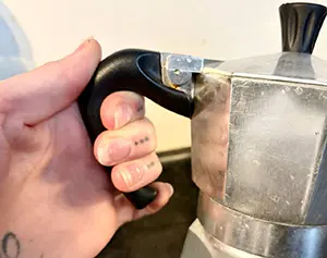 A close up of the moka pots handle in use